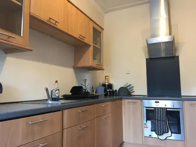 a kitchen with wooden cabinets and a stove top oven at Scotstoun 1 Bed Flat in Glasgow