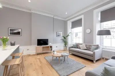 a white living room with a couch and a table at JOIVY Spacious Apartment close to Princes Street in Edinburgh