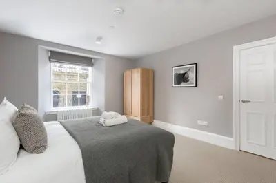 a bedroom with a large bed and a window at JOIVY Luxurious Home near Haymarket Station in Edinburgh