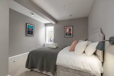 a bedroom with a bed with white sheets and pillows at JOIVY Luxurious Home near Haymarket Station in Edinburgh