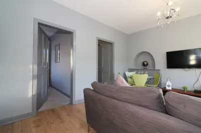 a living room with a couch and a tv at Signature - Burnbank House in Hamilton