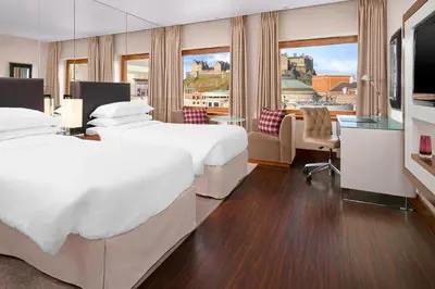 a hotel room with two beds and a large window at Sheraton Grand Hotel & Spa in Edinburgh