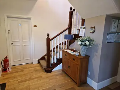 a hallway with a staircase with a vase of flowers at Craigbank Guest House in Crianlarich