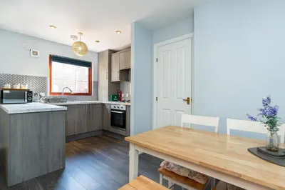 a kitchen with a wooden table and a dining room at One Bedroom ground floor flat in Stirling