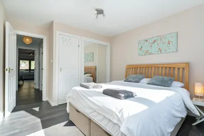 a bedroom with a large bed with white sheets at One Bedroom ground floor flat in Stirling