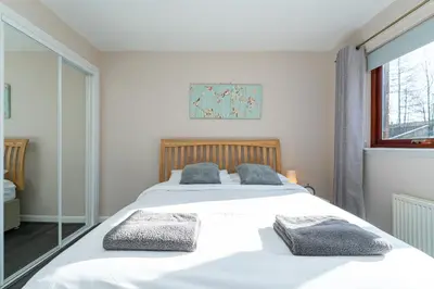 a bedroom with a large white bed with two pillows at One Bedroom ground floor flat in Stirling