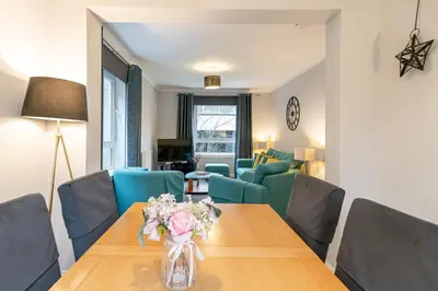 a living room with a wooden table and blue chairs at Ground-fl Two Bedroom Apartment in Bridge of Allan in Bridge of Allan