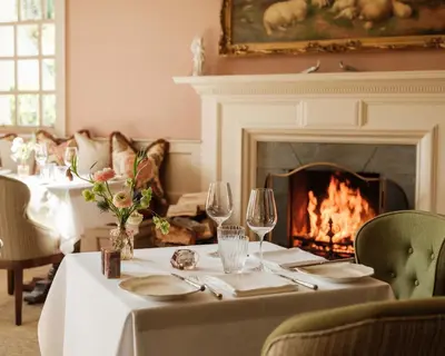 a dining room with a table and a fireplace at The Fortingall in Kenmore