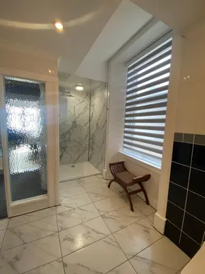 a bathroom with a shower and a bench next to a window at Barriemore Oban in Oban