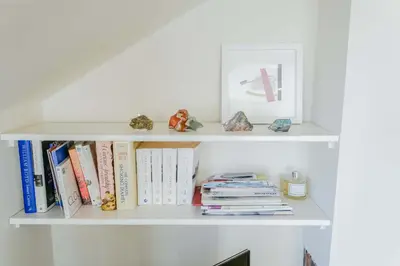 a white book shelf with books and toys on it at Sophisticated Edinburgh Apartment in City Centre in Edinburgh