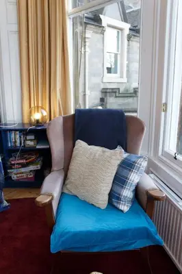 a chair with a pillow in a room with a window at Traditional Apartment oer the Meadows in Edinburgh