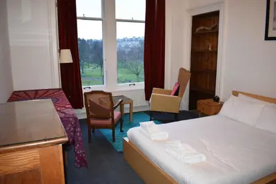 a hotel room with a bed and a table and chairs at Traditional Apartment oer the Meadows in Edinburgh