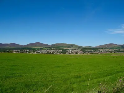 a field of green grass with a city in the background at Underneath the Arches in Penicuik