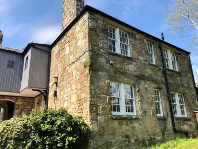 an old stone building with white windows and a chimney at Underneath the Arches in Penicuik