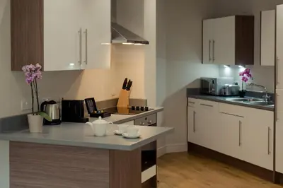 a kitchen with white cabinets and a counter top at PREMIER SUITES PLUS Glasgow Bath Street in Glasgow