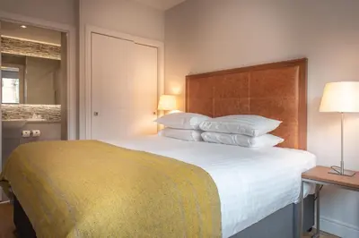 a bedroom with a large bed with white sheets and pillows at PREMIER SUITES PLUS Glasgow Bath Street in Glasgow