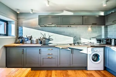 a kitchen with gray cabinets and a washer and dryer at Glasgow City Flats in Glasgow