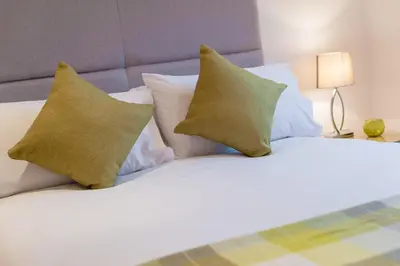 a white bed with four pillows on top of it at Glasgow City Flats in Glasgow