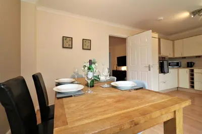 a dining room with a wooden table and a kitchen at Signature - Angus House Glasgow in Glasgow