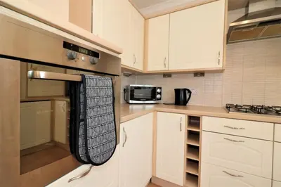 a kitchen with white cabinets and a black towel hanging from the oven at Signature - Angus House Glasgow in Glasgow