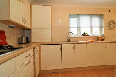 a kitchen with white cabinets and a sink and a window at Signature - Angus House Glasgow in Glasgow