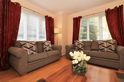 a living room with two couches and a vase with flowers at Signature - Angus House Glasgow in Glasgow