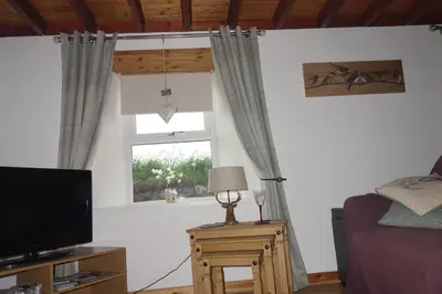 a living room with a television and a window at 3 Knocknaha Cottage in Campbeltown