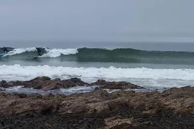 a person riding a wave on a surfboard in the ocean at 3 Knocknaha Cottage in Campbeltown