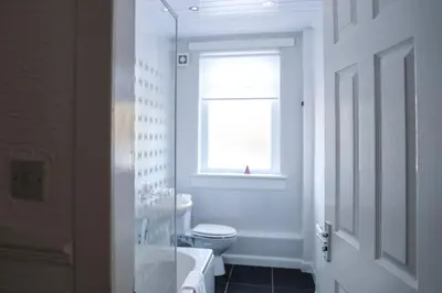 a white bathroom with a toilet and a window at Meadowburn View in Wishaw