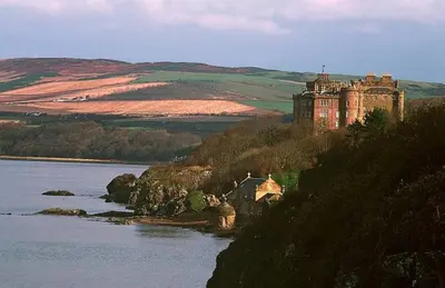 a castle on a hill next to a body of water at Dairy Cottage in Ayr