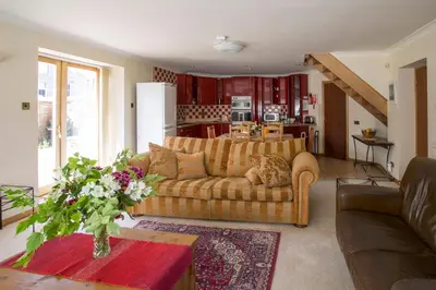 a living room with a couch and a kitchen at Dairy Cottage in Ayr