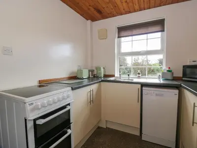 a kitchen with a stove and a sink and a window at Rose Cottage in Stranraer