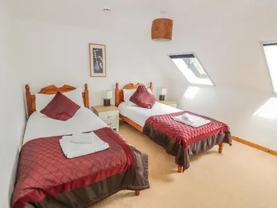 a bedroom with two beds with red comforter at The Dairy in Newton Stewart