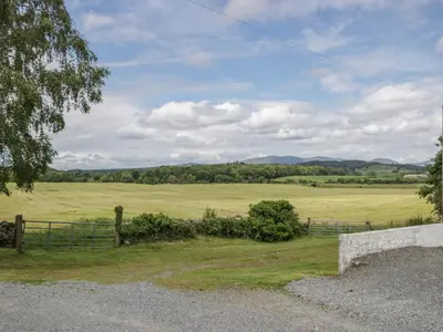 a field of green grass with a fence and trees at The Dairy in Newton Stewart