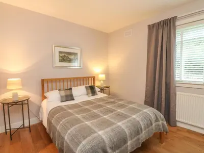 a bedroom with a bed and a window at Holly Cottage in Glencoe