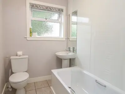 a white bathroom with a toilet and a sink at Holly Cottage in Glencoe