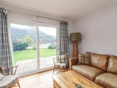a living room with a couch and a large window at Holly Cottage in Glencoe