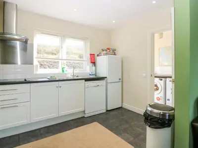 a kitchen with white cabinets and white appliances at Driftwood Cottage in Craignure