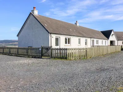 a white house with a fence in front of it at Driftwood Cottage in Craignure
