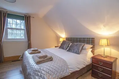 a bedroom with a bed with two towels on it at Craigievern Cottage in Drymen