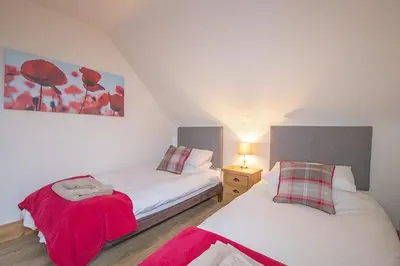 a bedroom with two beds with red flowers on the wall at Craigievern Cottage in Drymen