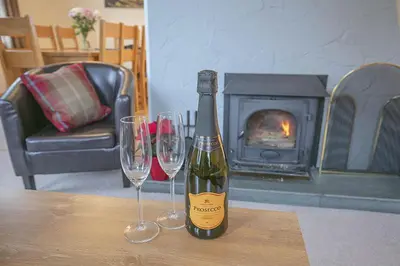 a bottle of wine and two wine glasses on a table at Craigievern Cottage in Drymen