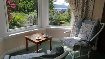 a room with two chairs and a table and two windows at The Old Cottage in Arduaine