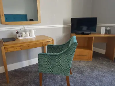 a desk and a chair next to a desk with a television at Ardshiel Hotel in Campbeltown