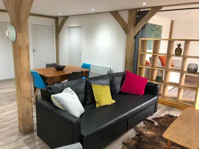 a living room with a black leather couch with colorful pillows at Finlaystone Family Barn in Port Glasgow