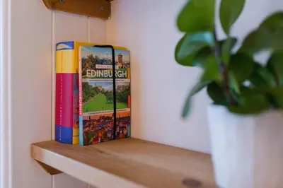 two books sitting on a shelf next to a plant at Historic Edinburgh 1890s Home Turned Relaxing Retreat in Edinburgh