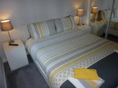 a bedroom with a bed with two night stands and two lamps at Paisley Central Apartment #2 in Paisley