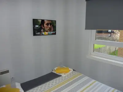 a tv hanging on a wall in a bedroom at Paisley Central Apartment #2 in Paisley
