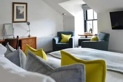 a hotel room with two beds and two chairs at The Douglas Hotel in Brodick