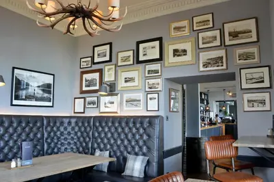 a dining room with a bench and pictures on the wall at The Douglas Hotel in Brodick